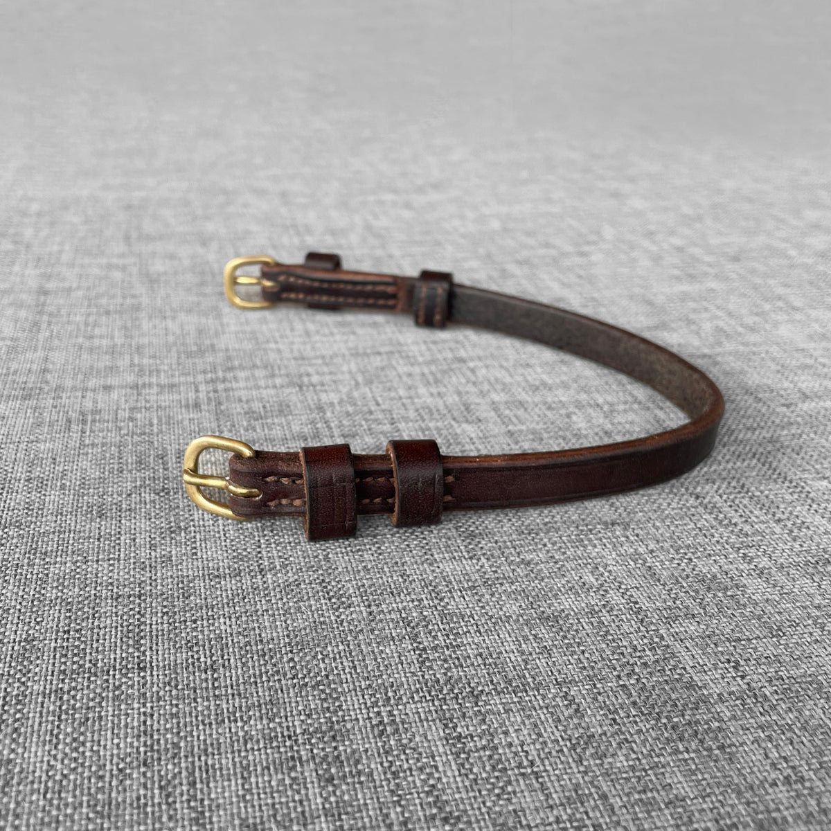 Attache de tetiere en cuir brun avec deux boucles dorees, courbee