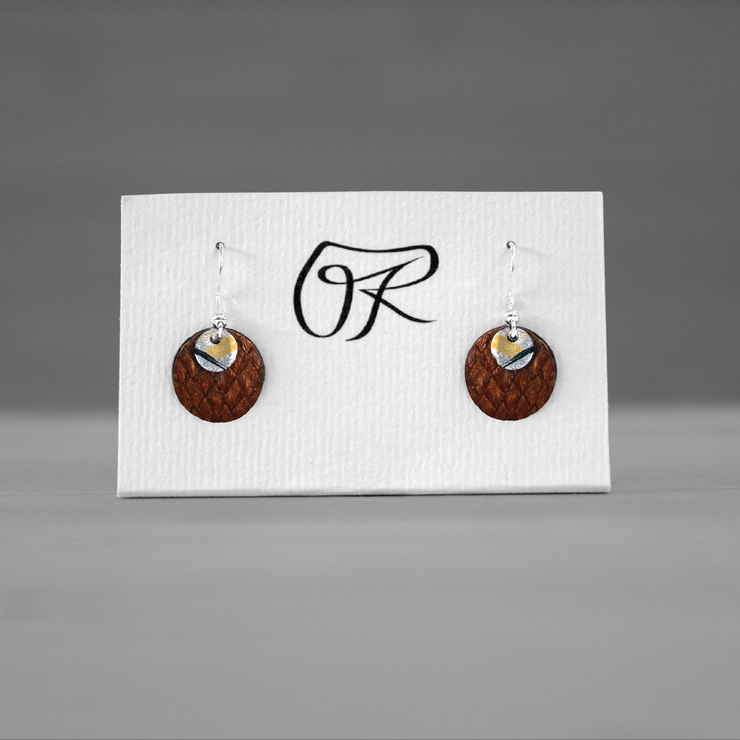 Boucles d'oreilles rondes en cuir de saumon brun sur carte de presentation, bijoux cuir Ruffieux Creation