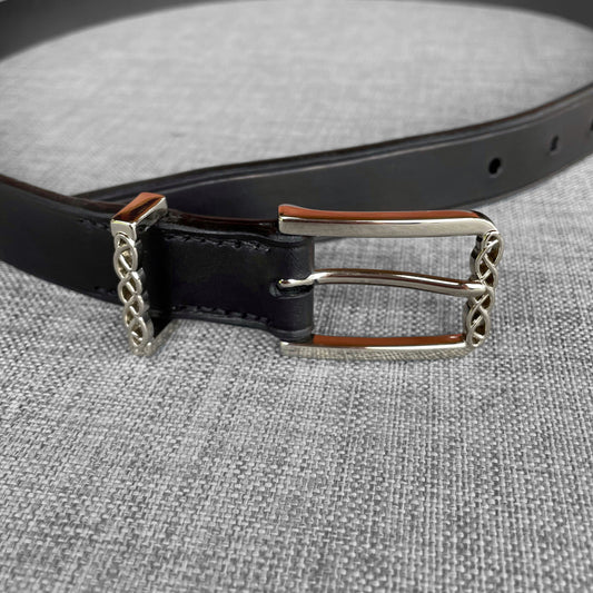 Detail de la boucle argentee tressee d'une ceinture en cuir noir avec doublure brune