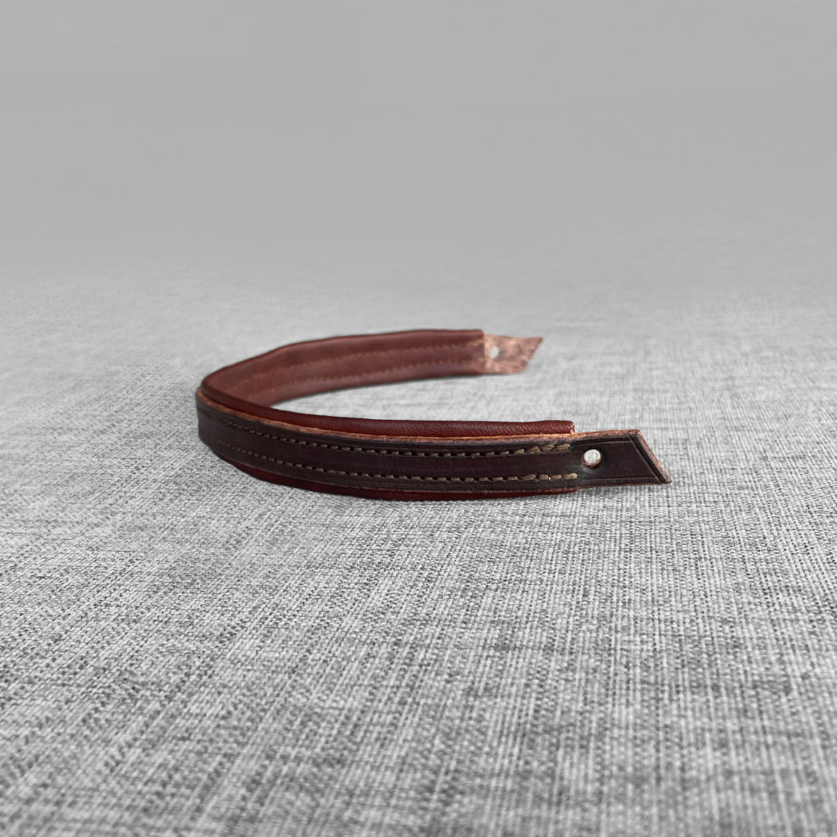 Frontal double en cuir brun, gros plan sur l'extremite pointue perforee