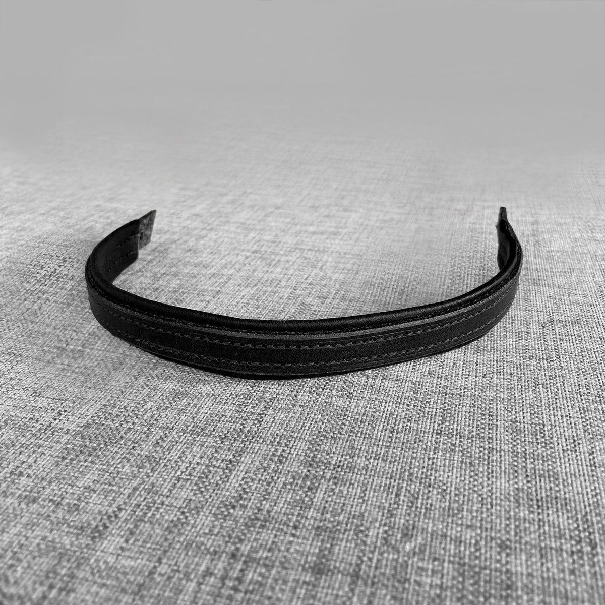 Frontal double en cuir noir pose a plat sur un fond gris