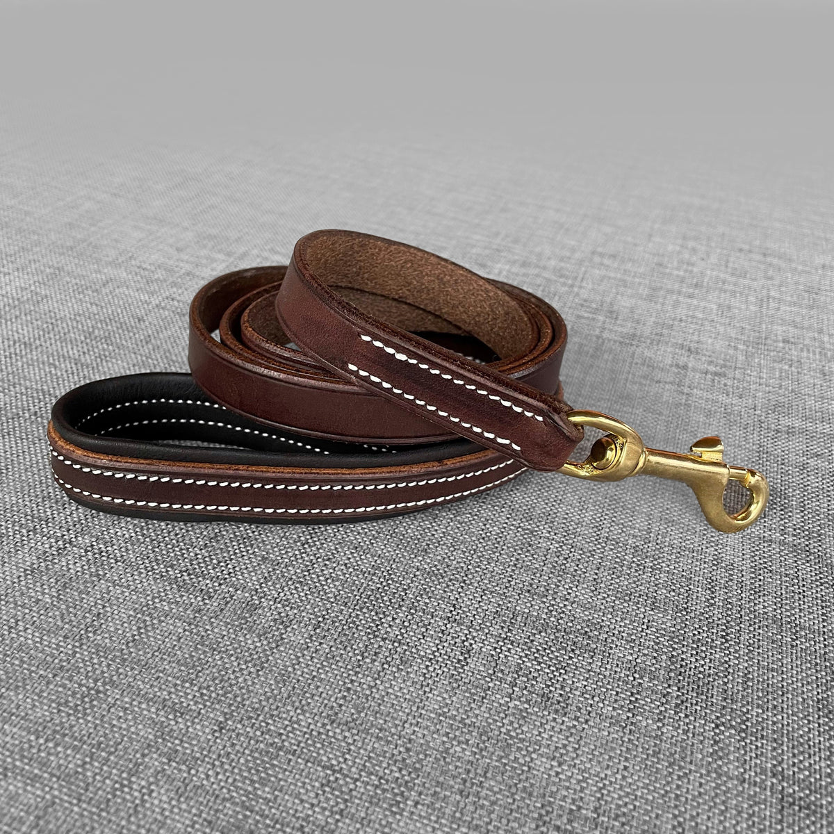 Laisse pour chien en cuir brun et noir enroulee avec mousqueton dore