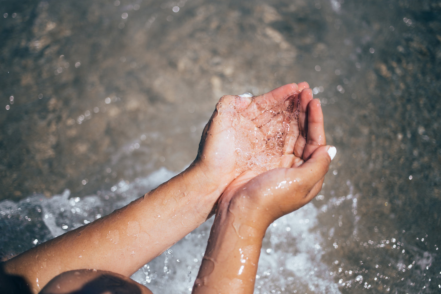 Mains en coupe recueillant de l'eau de mer sur une plage
