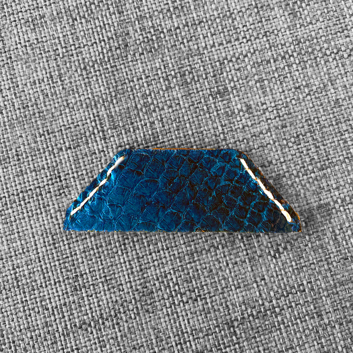 Marque-page en cuir bleu a motif ecailles avec surpiqure blanche, vue rapprochee