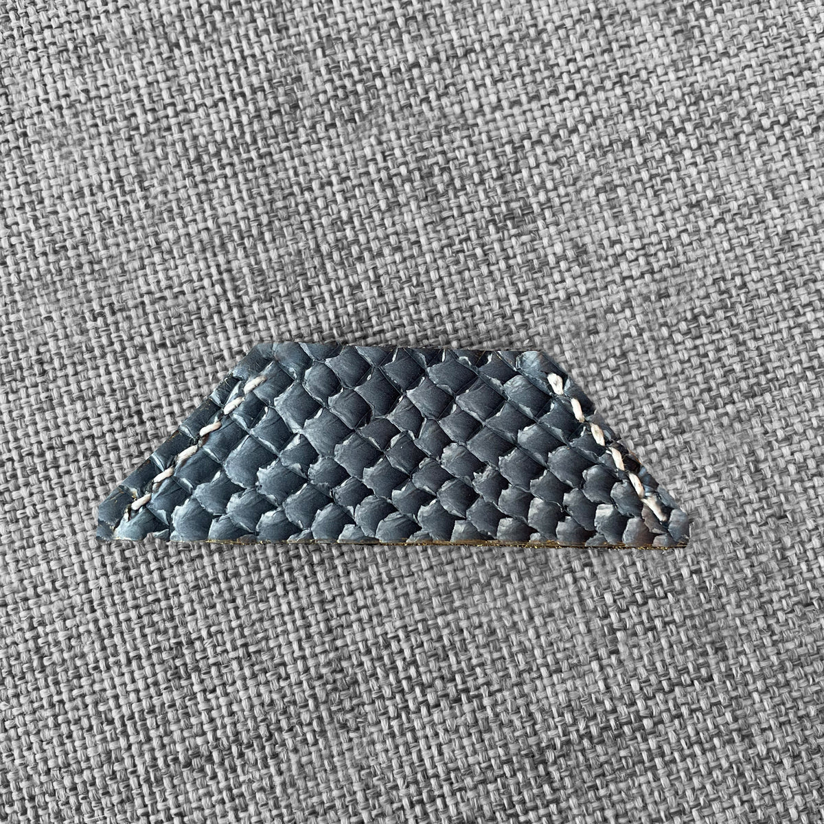 Marque-page en cuir gris a motif ecailles avec surpiqure blanche, vue rapprochee