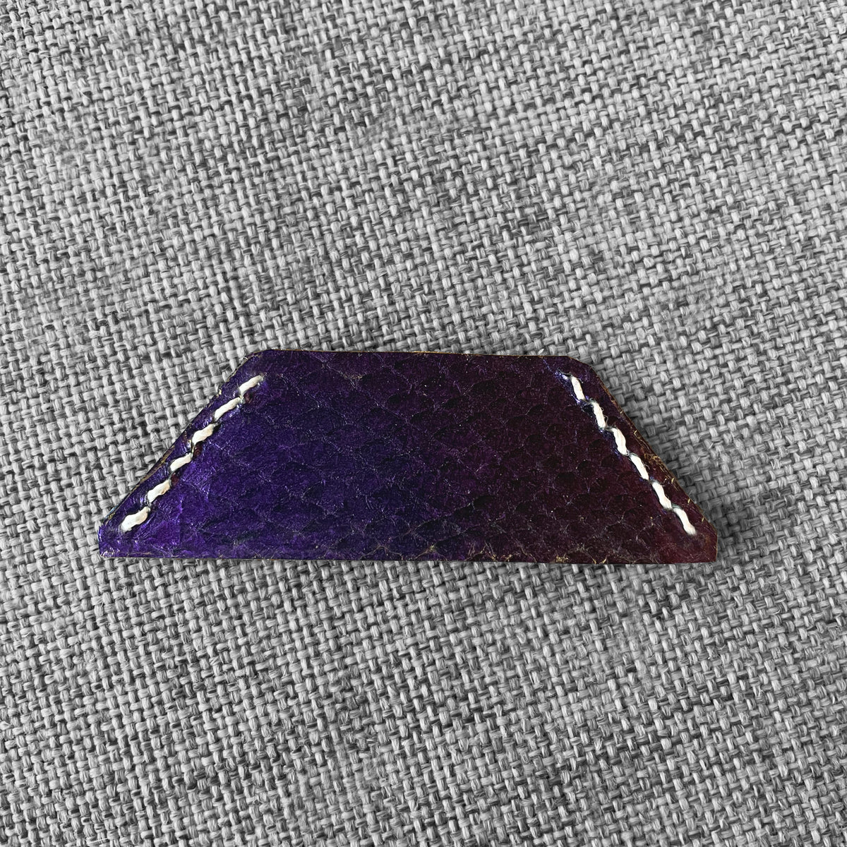 Marque-page en cuir violet a motif ecailles avec surpiqure blanche, vue rapprochee