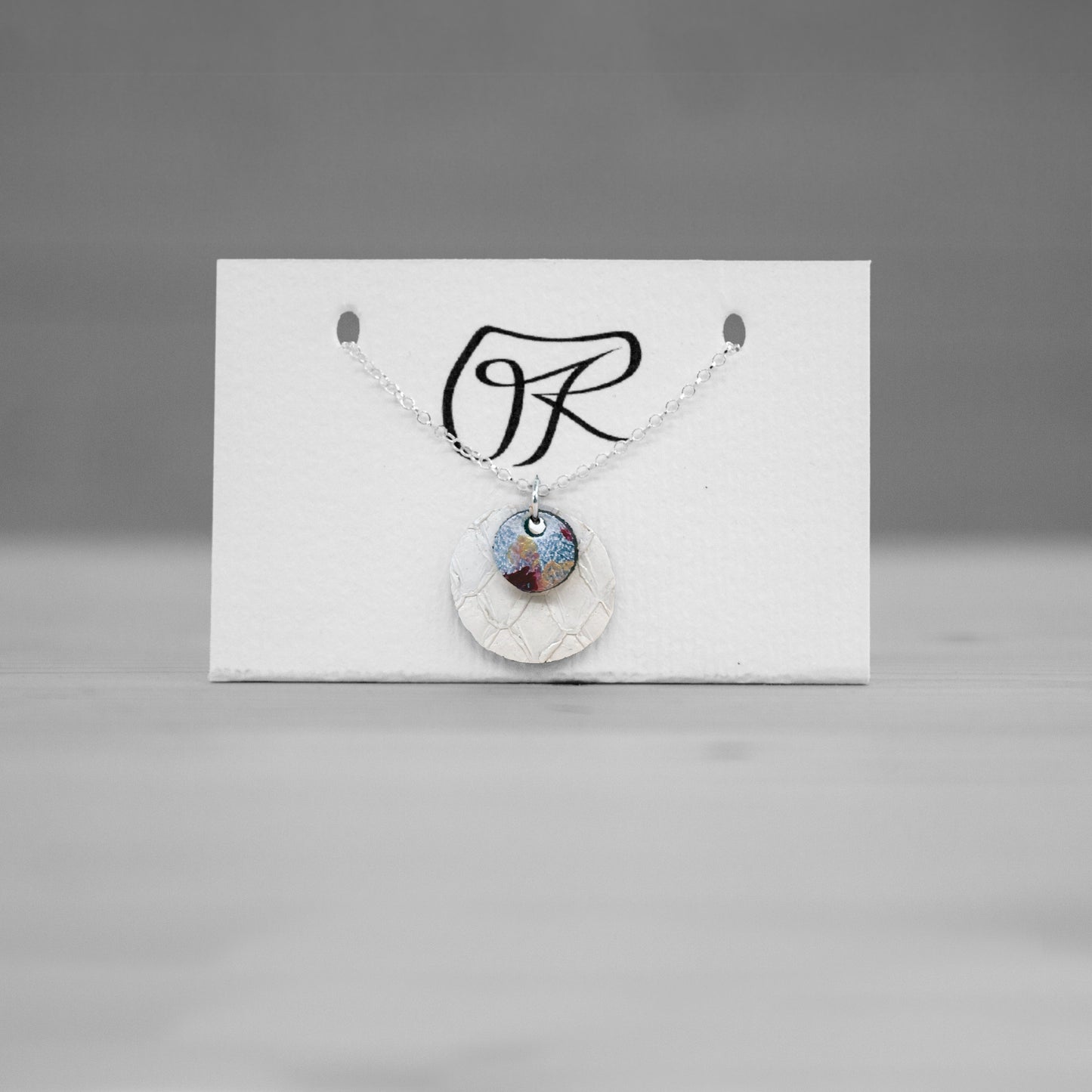 Pendentif rond en cuir de saumon blanc sur carte de presentation, bijou cuir Ruffieux Creation