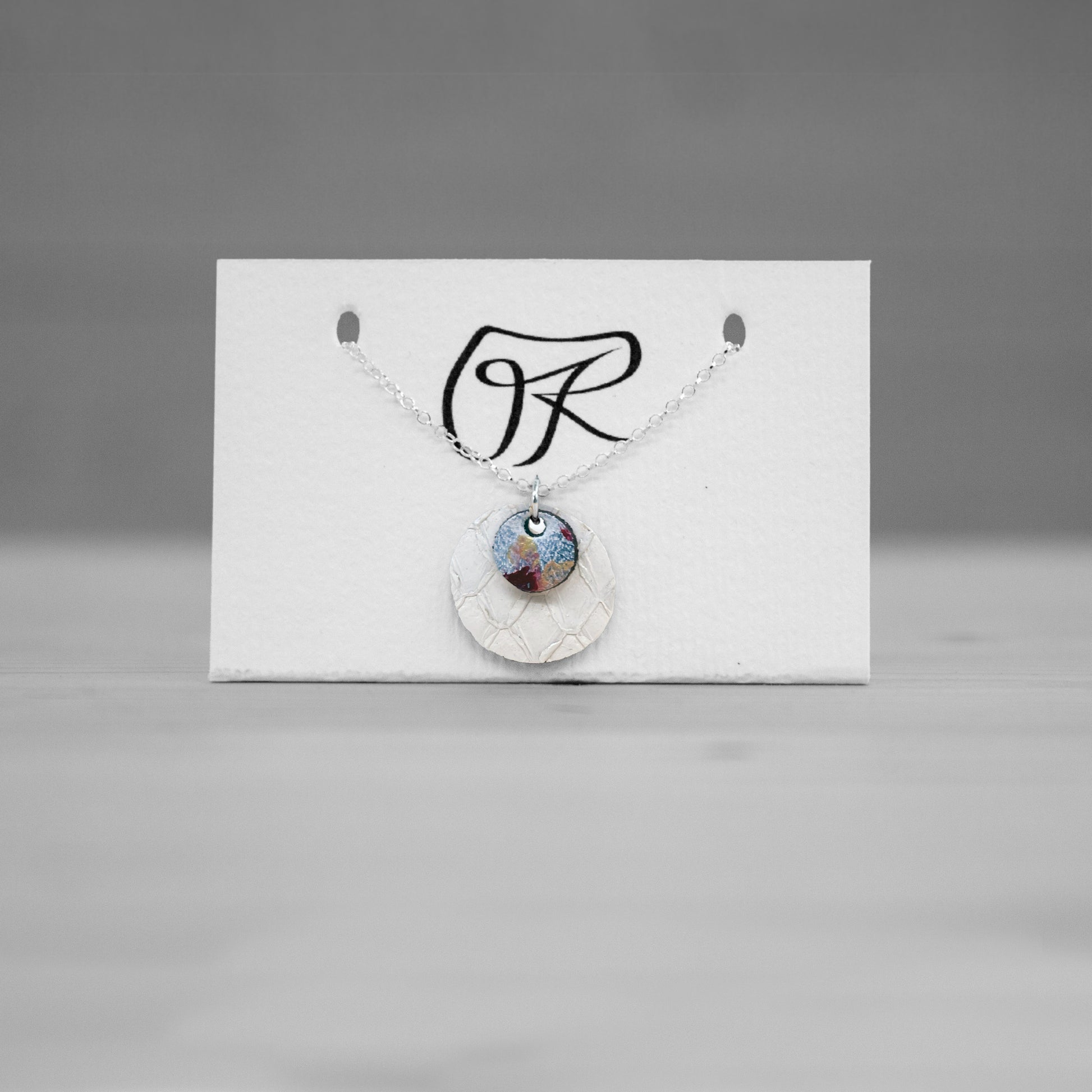 Pendentif rond en cuir de saumon blanc sur carte de presentation, bijou cuir Ruffieux Creation