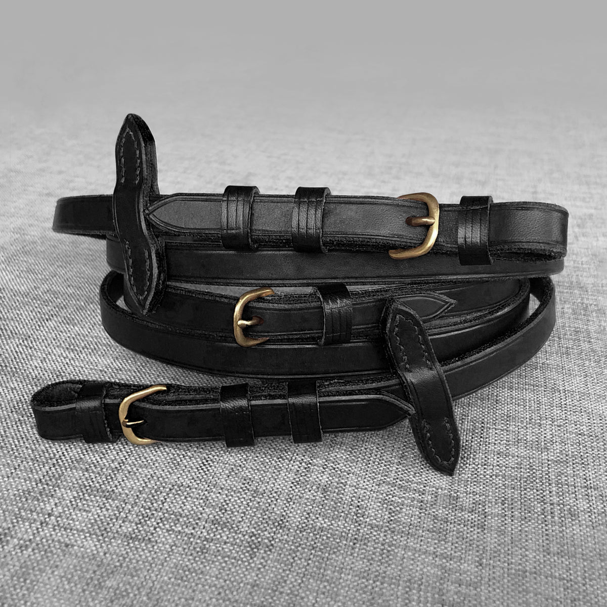 Renes en cuir noir enroulees avec boucles en laiton et arretoirs