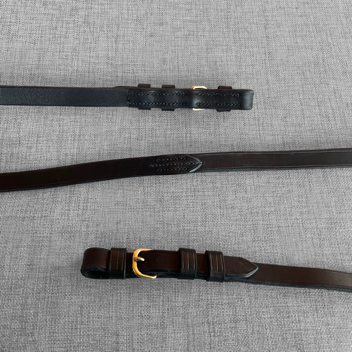 Renes de dressage en cuir noir avec boucles dorees, disposees en diagonale