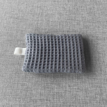 Sachet en tissu nid d'abeille gris avec boucle en tissu blanc pose sur un fond gris