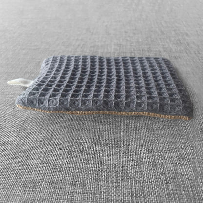 Sachet en tissu nid d'abeille gris avec doublure en jute pose sur un fond gris