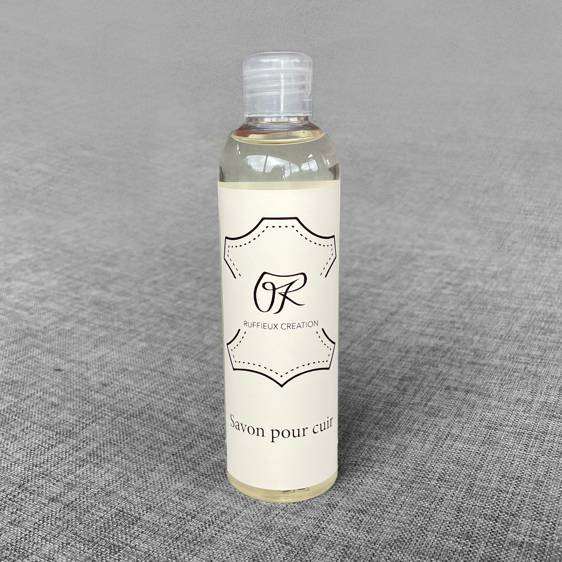 Flacon de savon pour cuir Ruffieux Creation pose sur un fond gris
