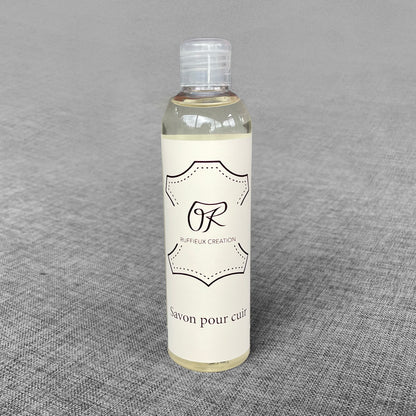 Flacon de savon pour cuir Ruffieux Creation pose sur un fond gris
