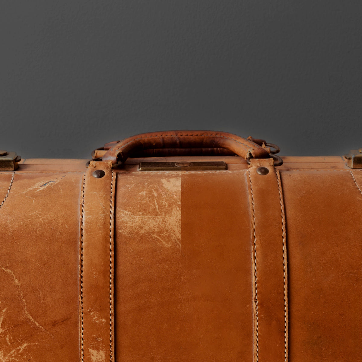 Poignée et coutures d'une valise vintage en cuir camel patiné
